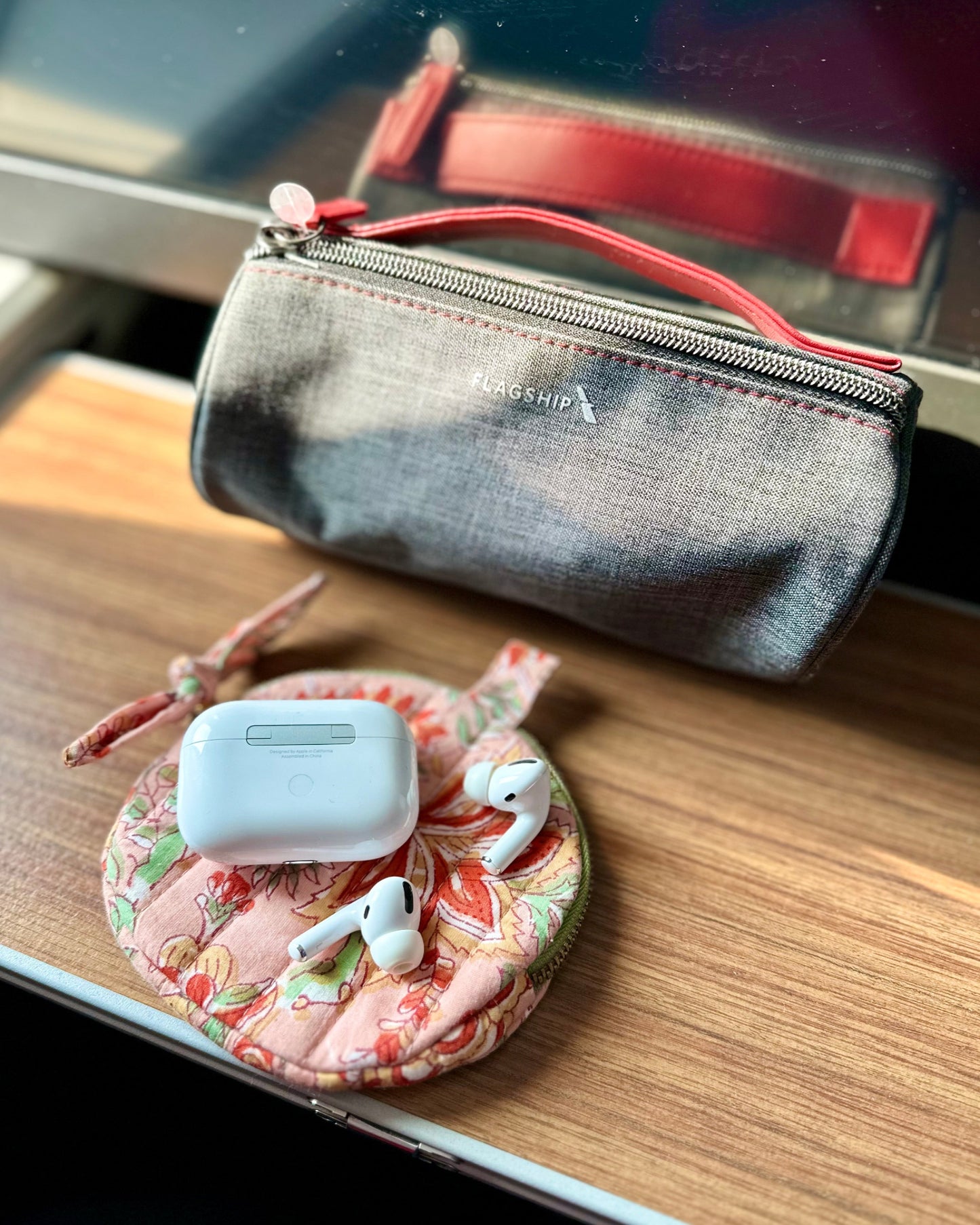 Small quilted circular pouch for earbuds storage on a wooden surface