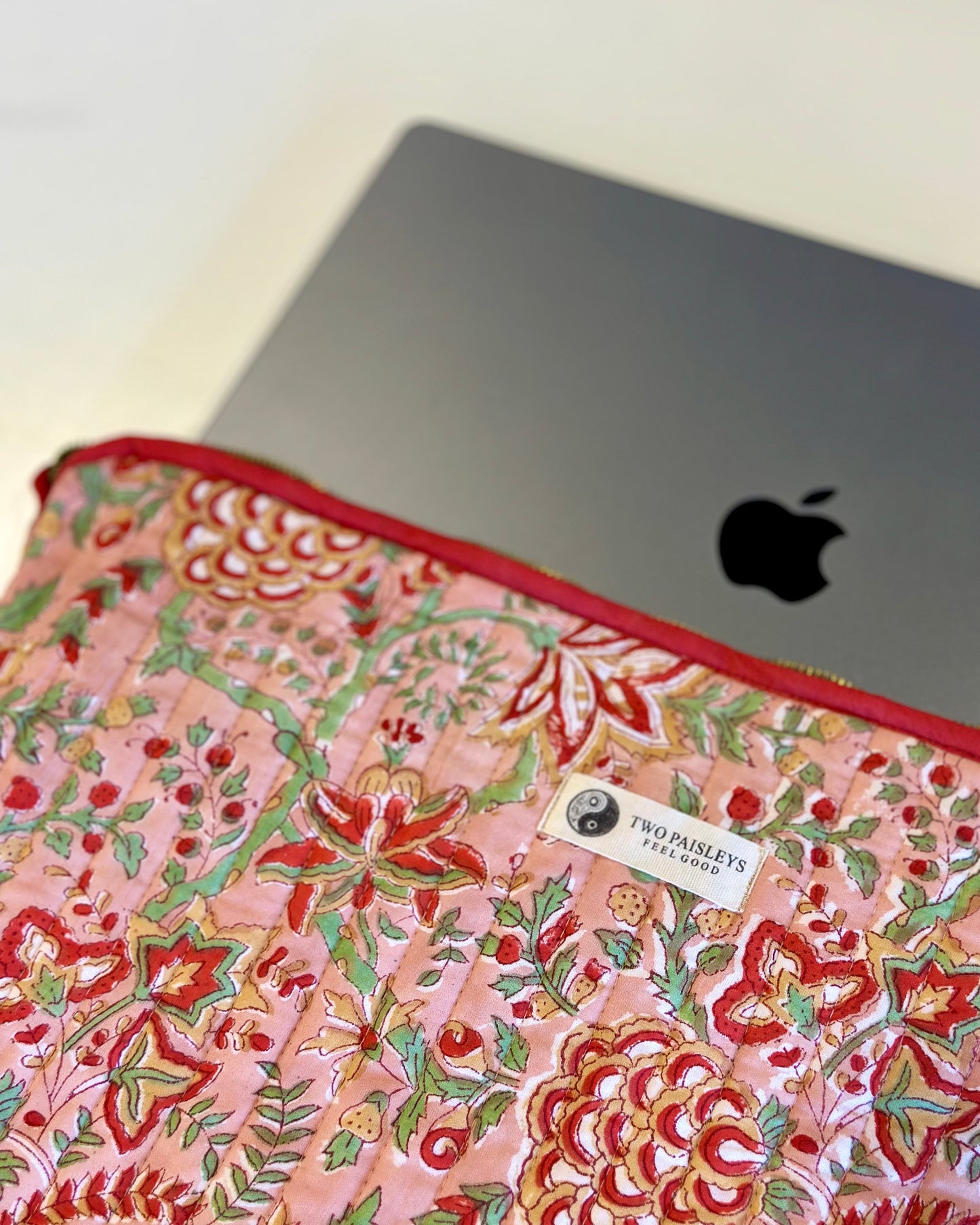 Floral-patterned pouch with a laptop and 'Two Parents' tag on a light background