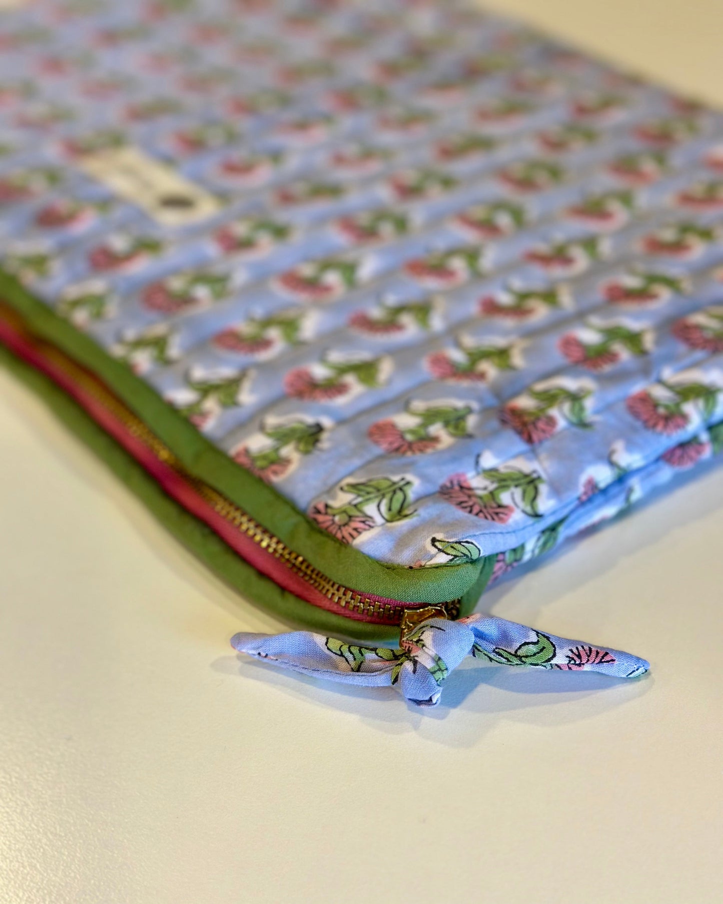 Floral-patterned fabric laptop sleeve with a zipper on a light background