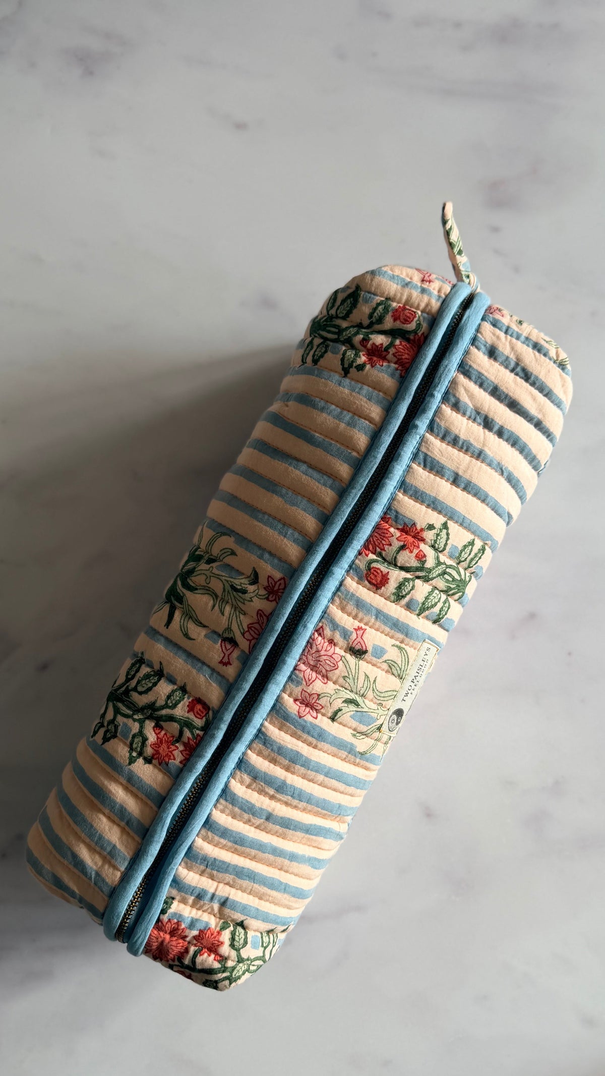 A top shot of the zipped up blue stripe floral hair accessories storage bag