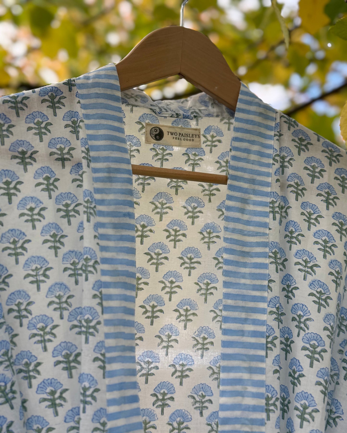 Close-up detail of the blue blossom block print cotton robe, showing the striped collar and "The Two Paisleys Feel Good" brand label.