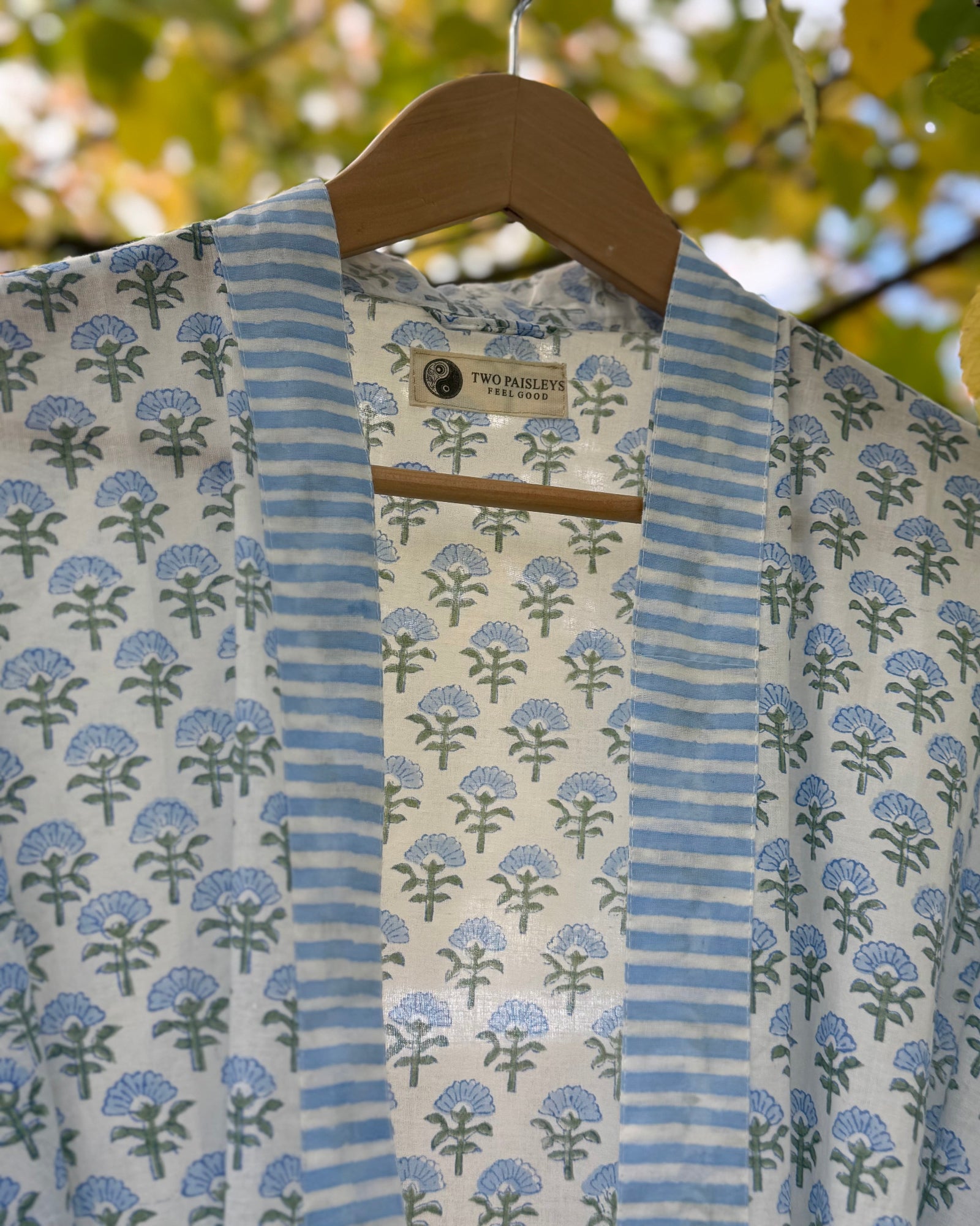 Close-up detail of the blue blossom block print cotton robe, showing the striped collar and "The Two Paisleys Feel Good" brand label.