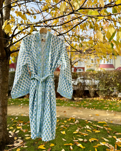 Full view of the 'Blue Blossom' hand block print waffle robe hanging on a tree with yellow leaves.