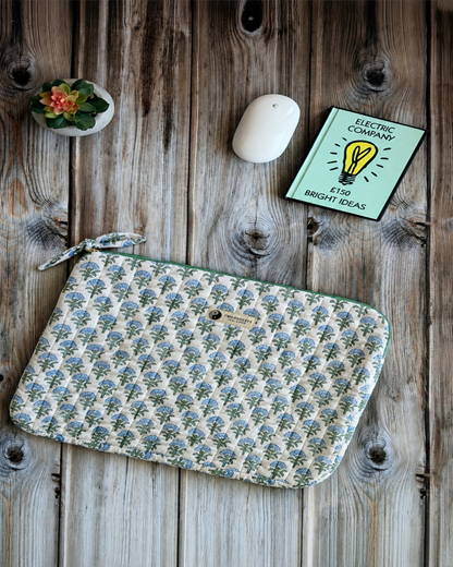 Blue & green floral pattern  laptop sleeve on a wooden desk with a plant and a wireless mouse.