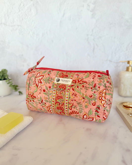 Floral patterned toiletry bag on a marble surface with a white background
