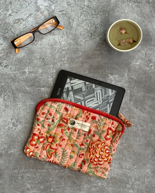 Lifestyle image of Coral Bloom Kindle sleeve with Kindle and tea.

