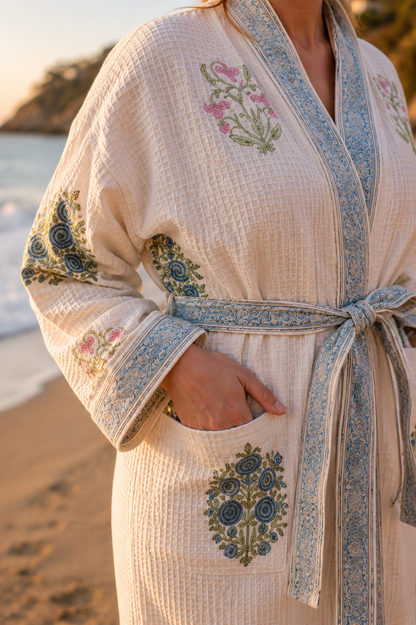 A close-up of a person wearing a cream-colored waffle-knit robe with blue & pink block print motif.