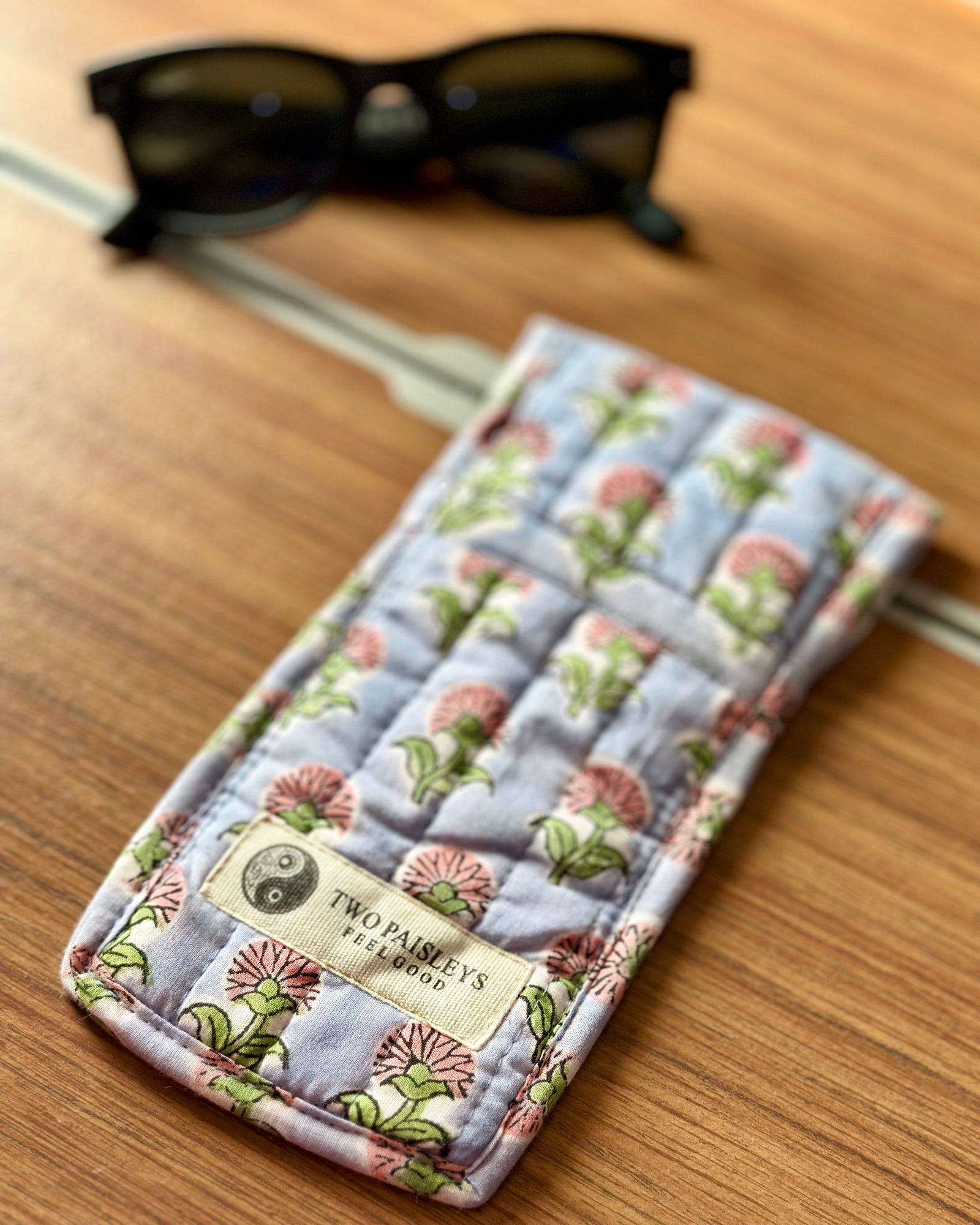 pink & purple Floral-patterned glass case with sunglasses on a wooden surface