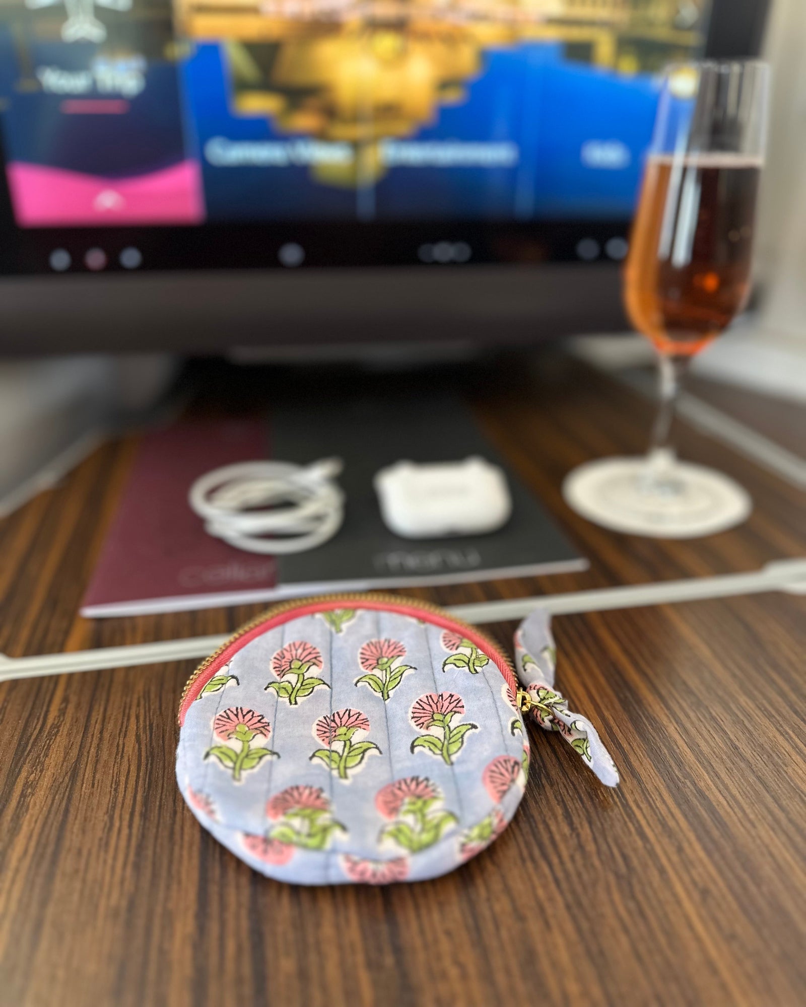 Round floral-jewellery  AirPods ear bud patterned storage pouch on a wooden surface with a blurred background
