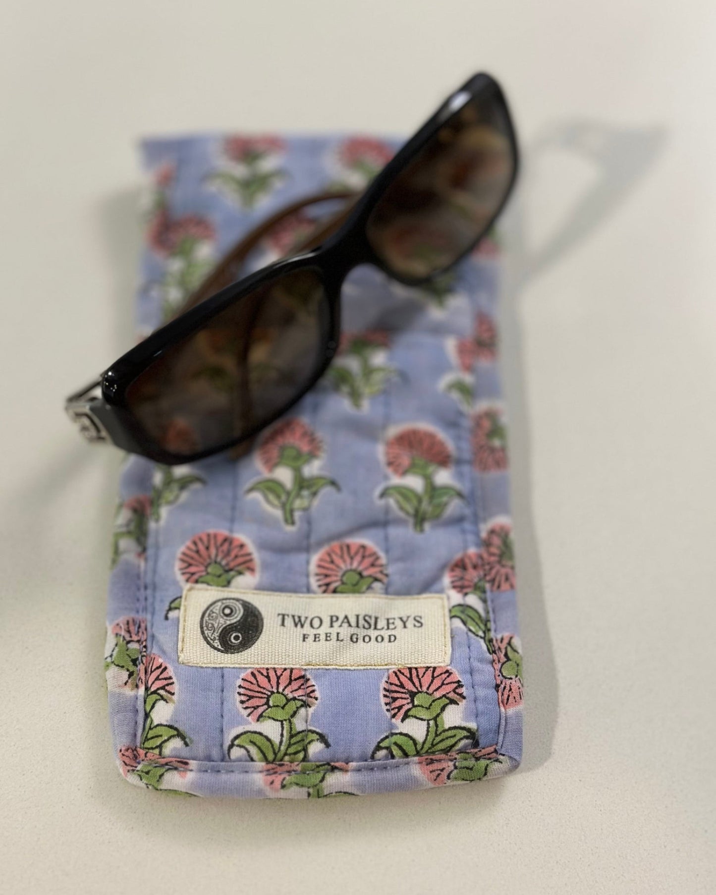 Floral sunglasses case with sunglasses on a white background