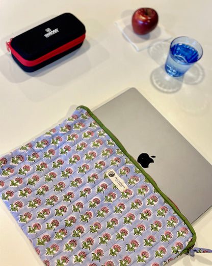 Floral patterned laptop sleeve on a laptop with an apple and pencil case in the background.