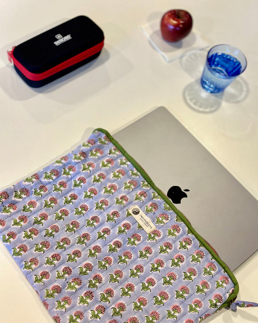 Floral patterned laptop sleeve on a laptop with an apple and pencil case in the background.
