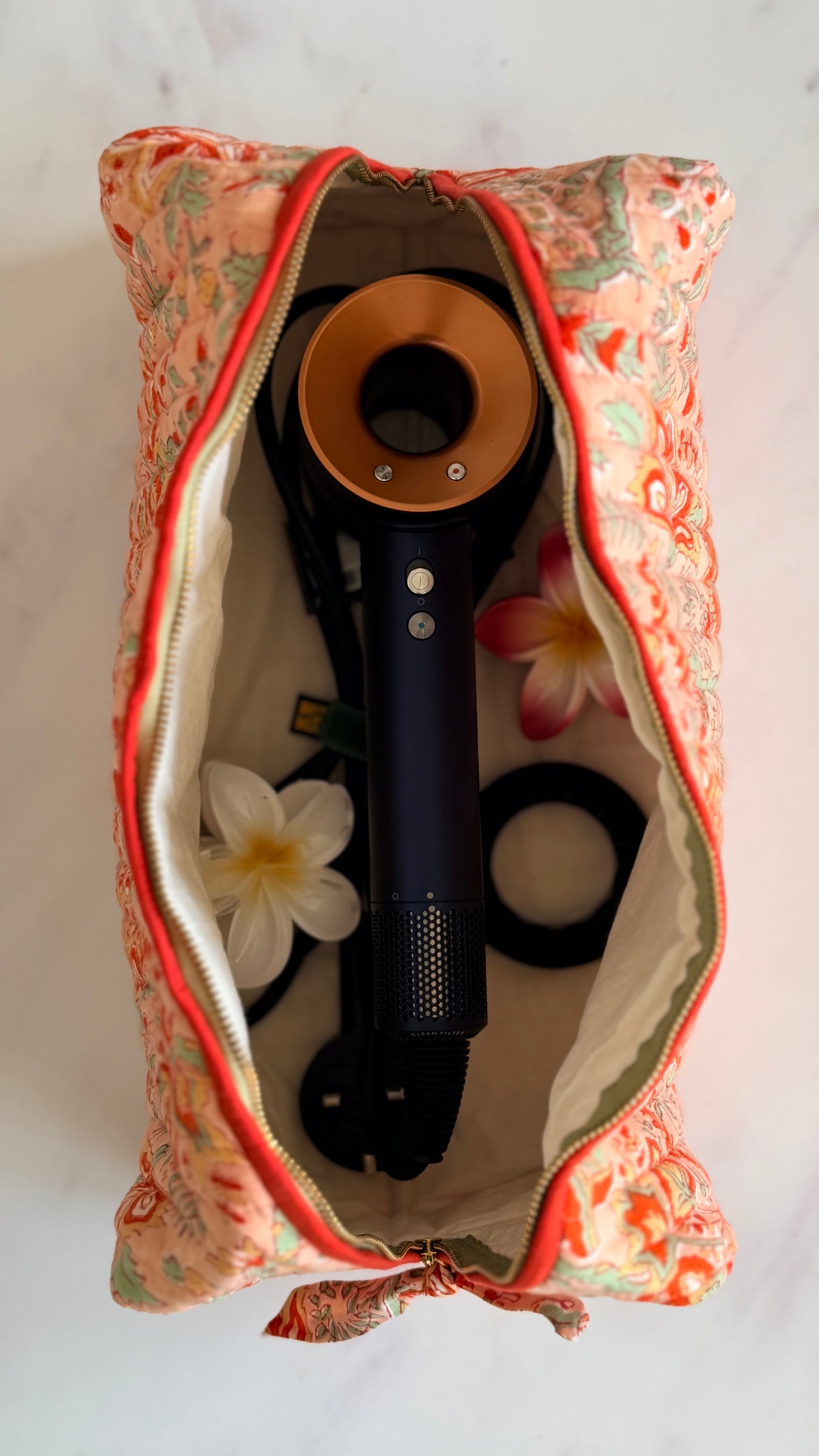 Top-down view inside Coral Floral quilted hair tools bag showing hair dryer stored safely, roomy cotton-lined travel organiser.