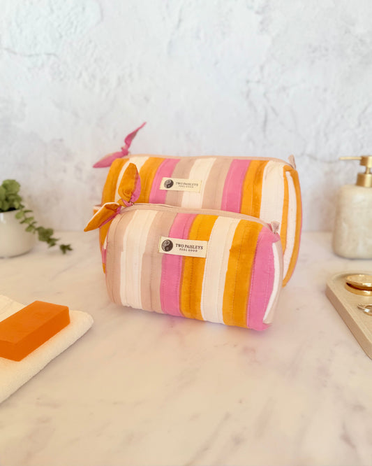 Striped toiletry bag on a marble surface with a white wall background