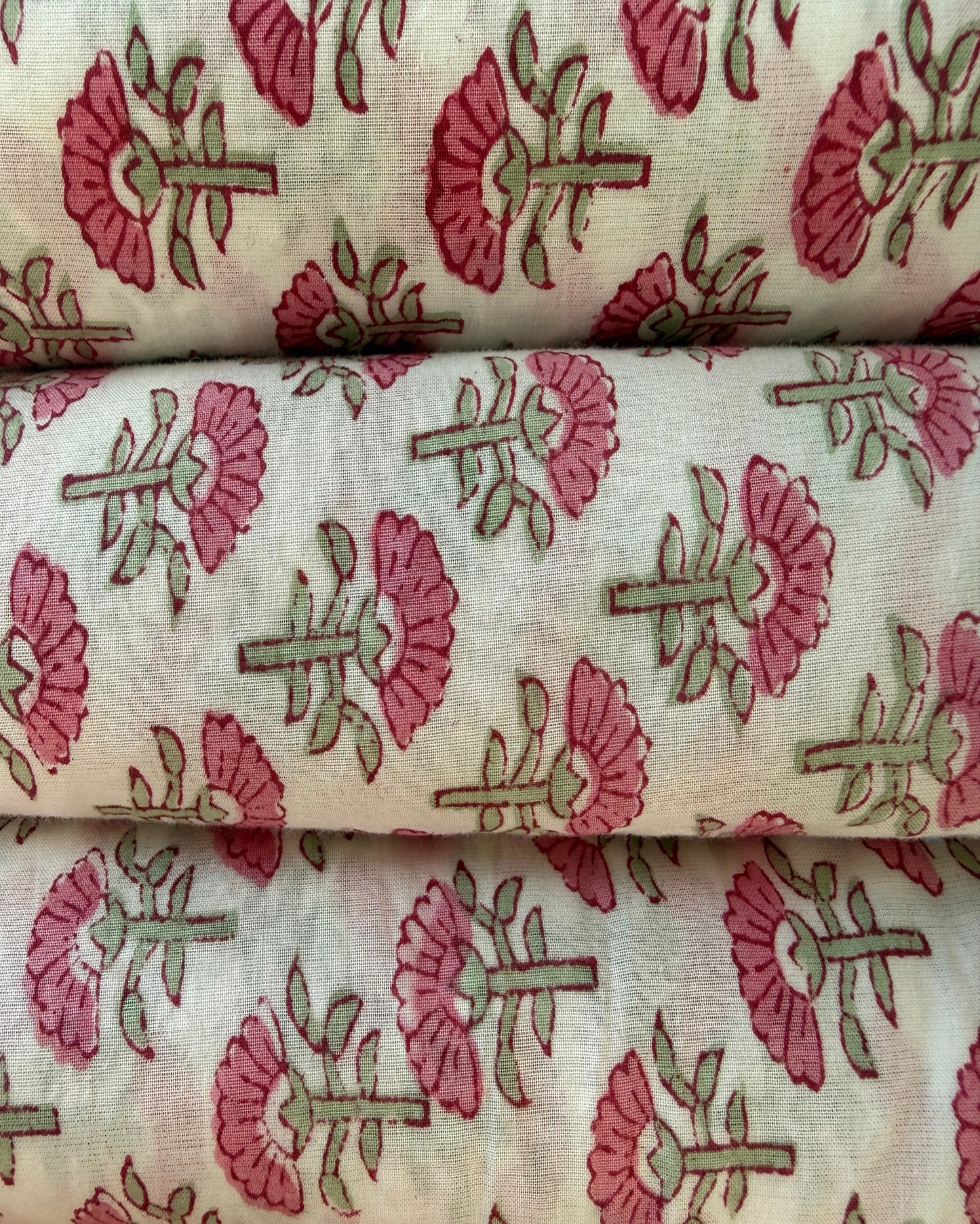 Stack of fabric with soft pink florals on an off  white background