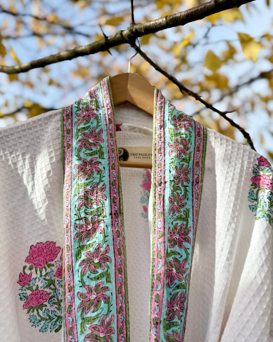 Blue & Pink Floral-patterned waffle robe  over a hanger with a blurred natural background