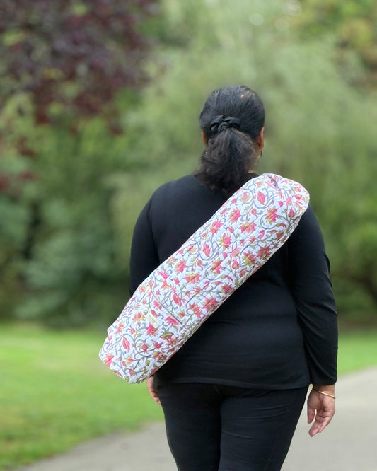 Woman carrying Rose Raga hand block printed cotton yoga mat cover with adjustable strap.