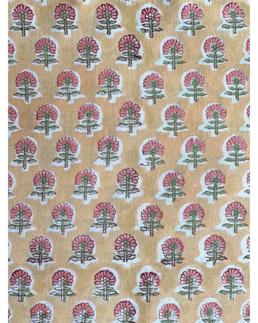 A close-up of the Sunset Orchard Hand Block Print Cotton Fabric, featuring a dusty rose floral buti on a warm, golden-orange background