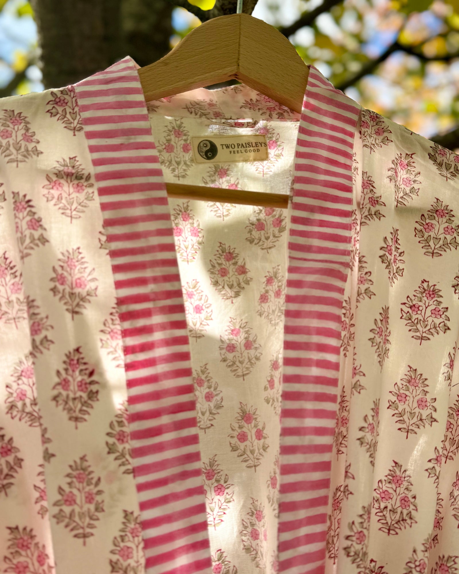 Close-up detail of the pink floral block print cotton robe, showing the striped collar and "The Two Paisleys Feel Good" brand label