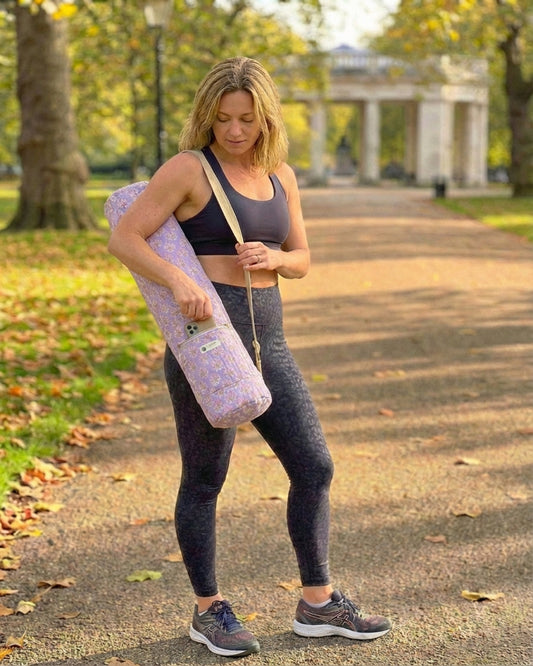Woman in fitness wear with yoga mat bag in a park.