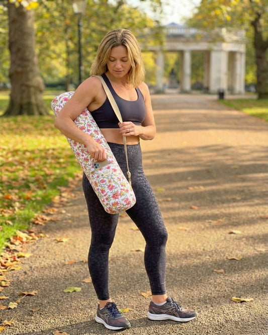 Woman holding a floral yoga mat in a park