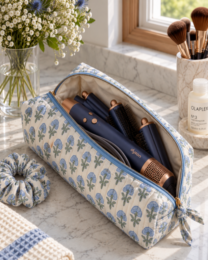 Open Two Paisleys Blue Blossom quilted cotton travel bag holding a Dyson Airwrap multi-styler and attachments on a vanity