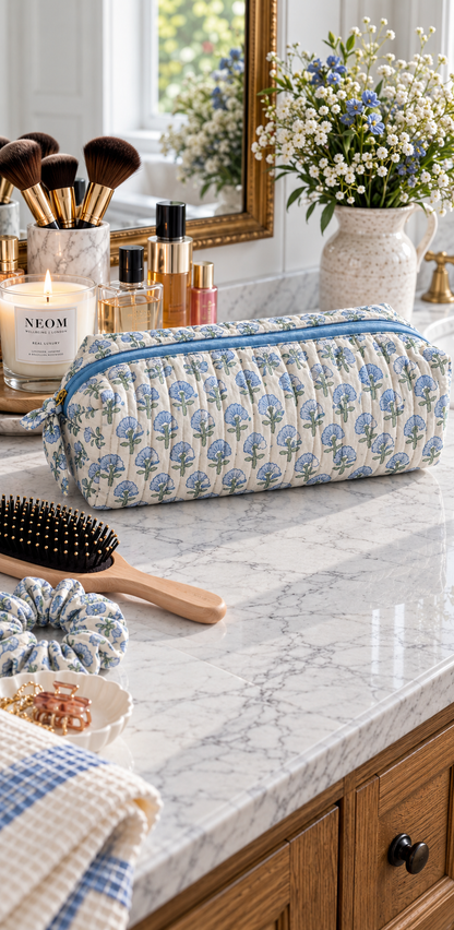 Two Paisleys Blue Blossom quilted cotton hair tools bag displayed on a marble bathroom vanity next to a candle and hairbrush