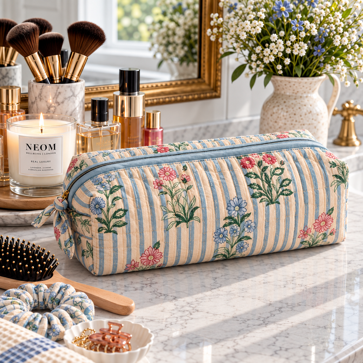 Two Paisleys Blue Stripe Floral quilted cotton hair tools bag in blue and cream block print displayed on a marble bathroom vanity next to a candle and hairbrush
