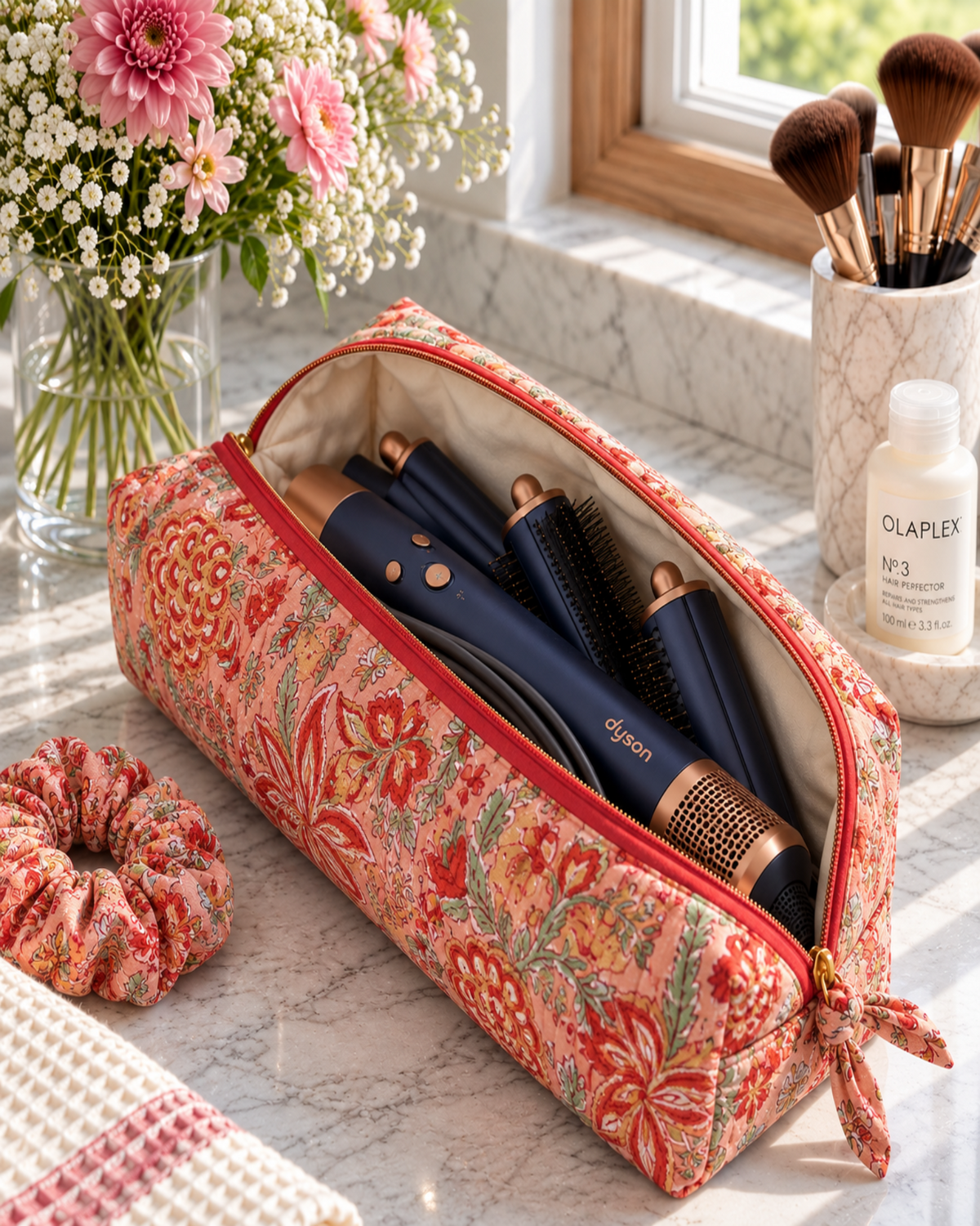Open Two Paisleys Coral Floral quilted cotton travel bag holding a Dyson Airwrap multi-styler and attachments on a vanity unit