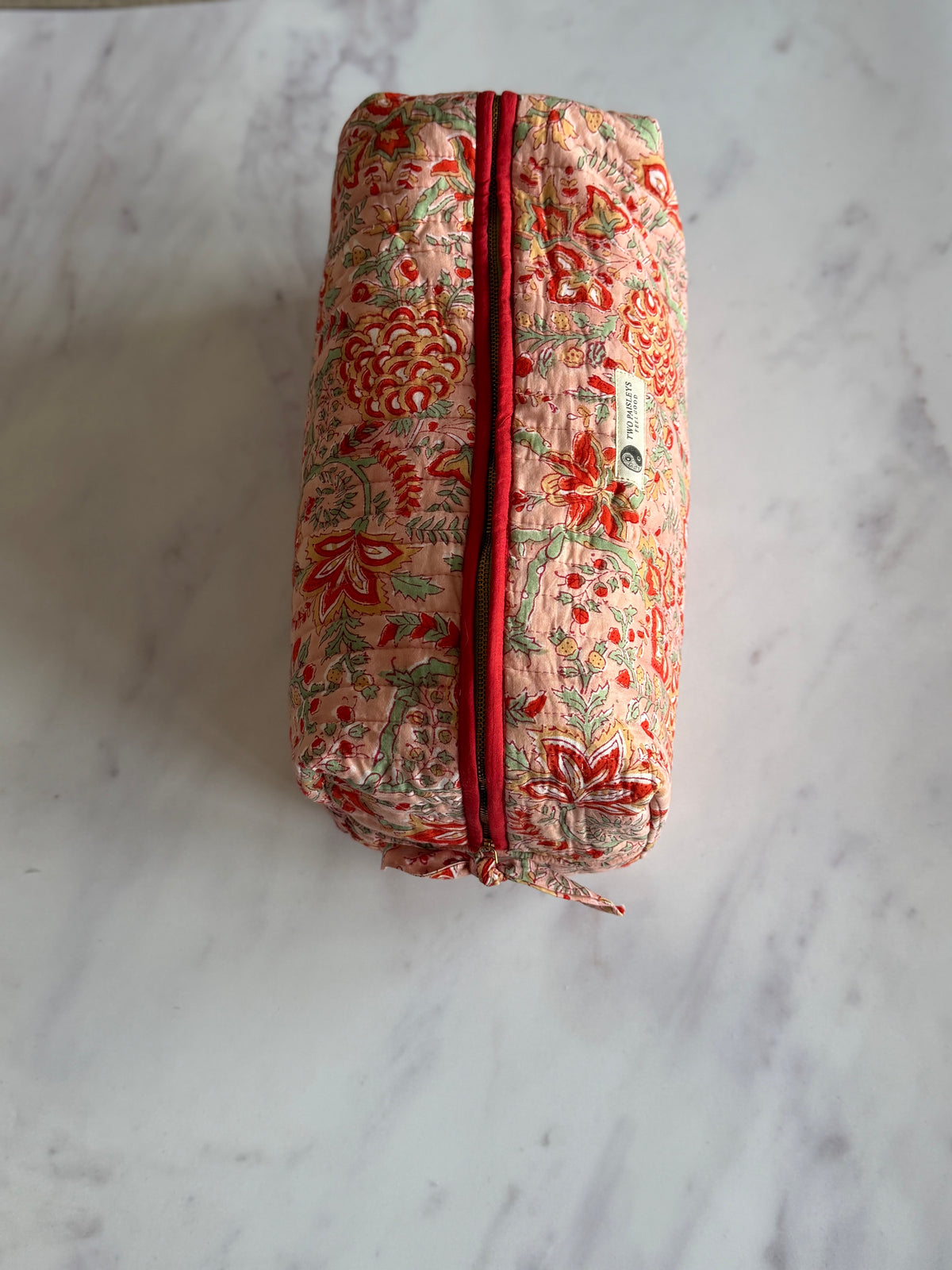 A top shot of a closed  quilted hair tools  bag with coral and terracotta florals
