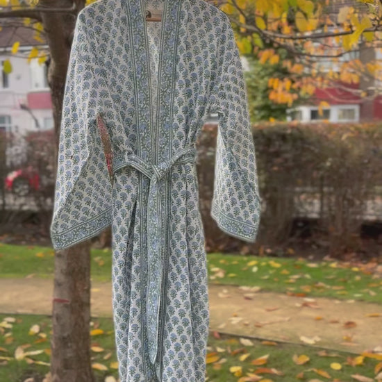 Full  movie view of the 'Blue Blossom' hand block print waffle robe hanging on a tree with yellow leaves.