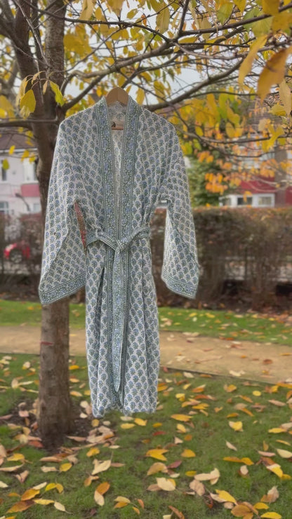 Full  movie view of the 'Blue Blossom' hand block print waffle robe hanging on a tree with yellow leaves.